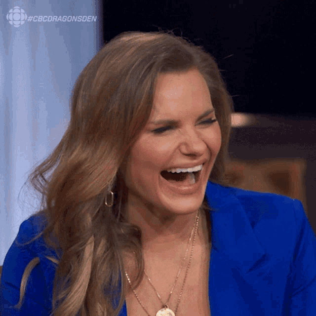 a woman in a blue jacket is laughing with her mouth open