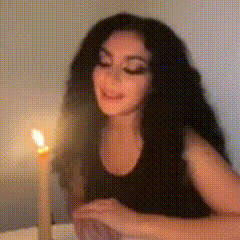 a woman is sitting at a table in front of a lit candle .