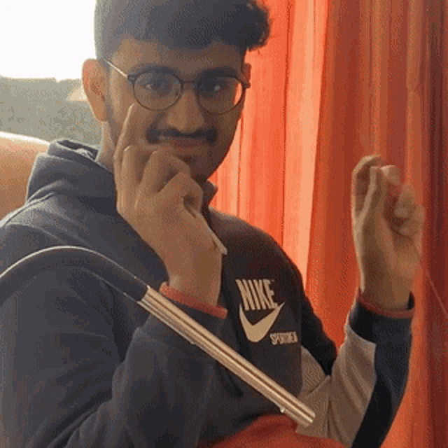 a man wearing glasses and a nike shirt holds a hookah