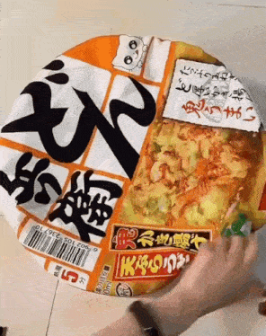 a person is opening a container of ramen with chinese writing on it