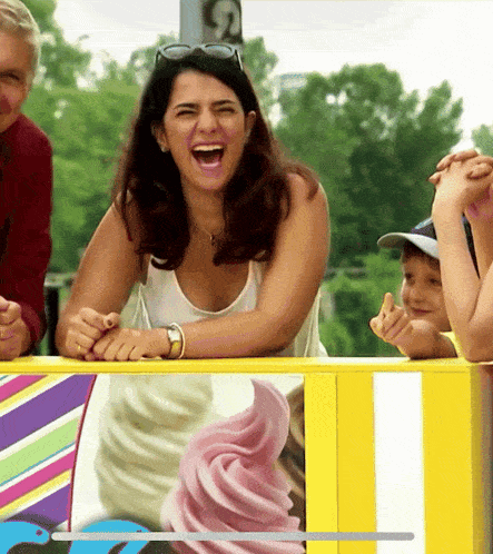 a woman is laughing in front of a sign that says ' ice cream ' on it