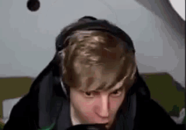 a man wearing headphones and a hoodie is looking at the camera .