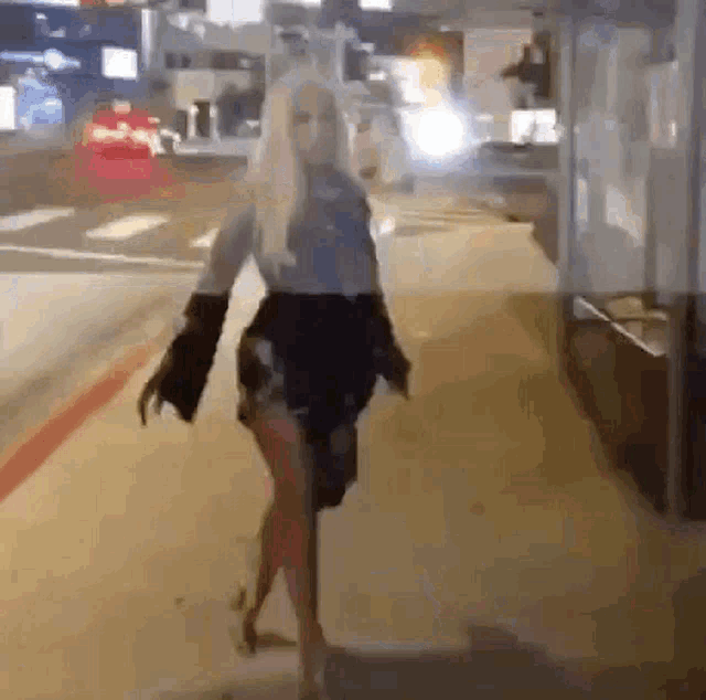 a woman is walking down a sidewalk at night