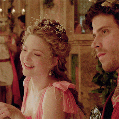 a woman in a pink dress is smiling next to a man in a red coat