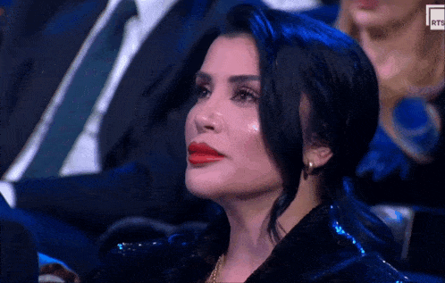 a woman sitting in a crowd with a rts logo on the bottom right corner of her face