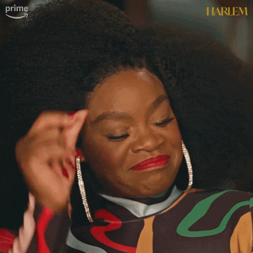 a woman with red nails is smiling in front of a harlem sign