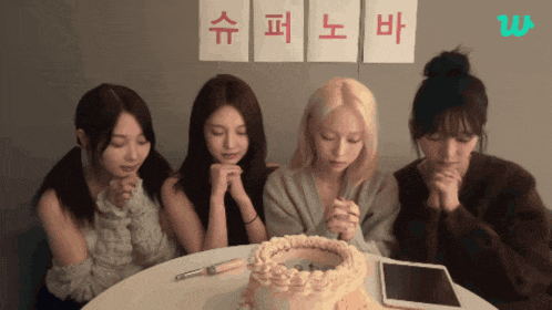 a group of girls praying in front of a cake with chinese writing on the wall