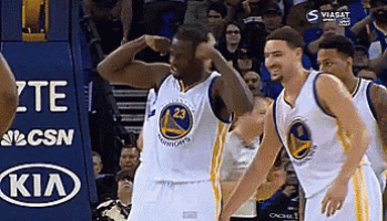 a golden state warriors basketball player flexes his muscles in front of a kia sign