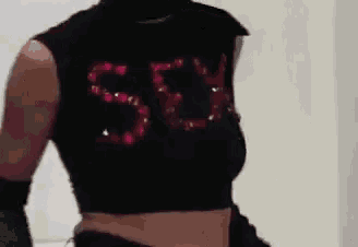 a woman wearing a black crop top with the letters sg on it .