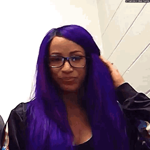 a woman with purple hair and glasses is standing in a room .