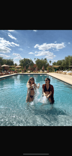 two women are splashing in a swimming pool
