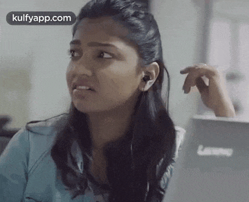 a woman wearing headphones is sitting in front of a lenovo laptop .