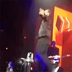 a man is standing upside down on a stage with a camera behind him