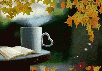 a cup with a heart shaped handle is on a table next to an open book