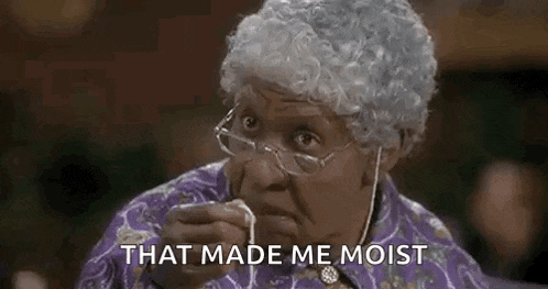 an elderly woman wearing glasses and a wig is eating a piece of food .