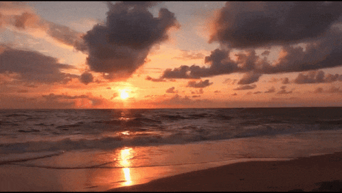 a sunset over the ocean with waves crashing on the shore