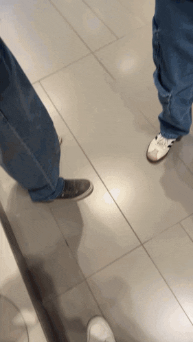 a person standing on a tiled floor wearing a pair of white shoes