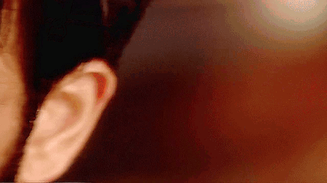 a close up of a person 's ear against a brown background