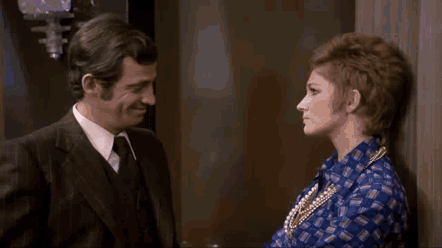 a man and a woman are standing next to each other and looking at each other in a room .