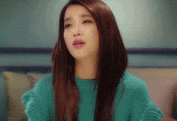 a woman with long hair is wearing a green sweater and making a funny face