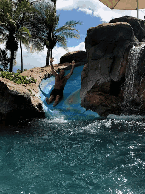 a man is sliding down a water slide in a swimming pool