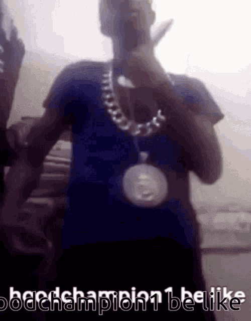 a man in a blue shirt is wearing a chain around his neck and a medal around his neck .