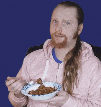 a man in a pink hoodie is holding a bowl of food