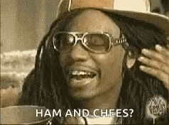 a man wearing sunglasses and a hat is smiling and saying ham and chees .