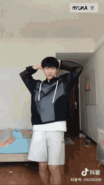a young man is standing in a room with a sign that says hyuka on it