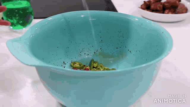 a blue bowl filled with green peppers and black pepper is made by animatica