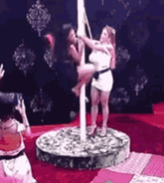 a woman is sitting on a pole with another woman standing behind her