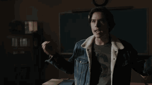 a man in a denim jacket says " it 's over " in a dark room