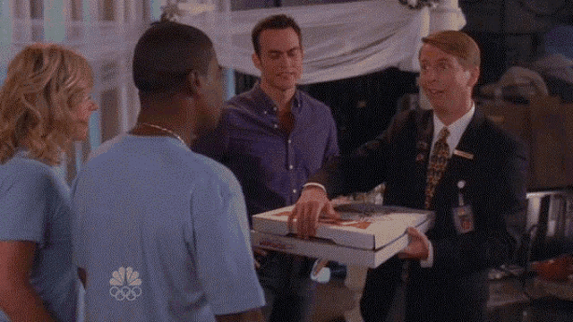 a man holding a pizza box with a nbc logo on it