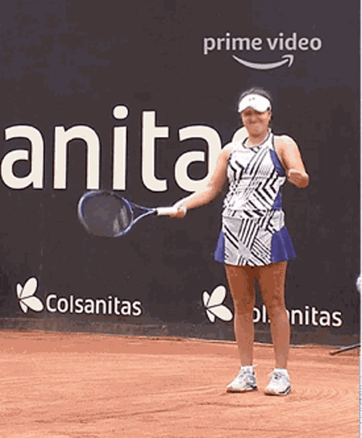 a woman is holding a tennis racquet in front of a wall that says prime video