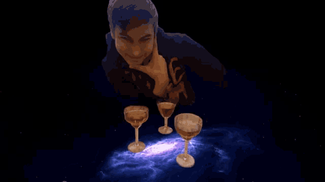 a man stands in front of a galaxy with three wine glasses