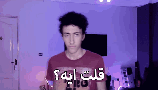 a man wearing a red shirt with the word pro on it stands in front of a purple wall