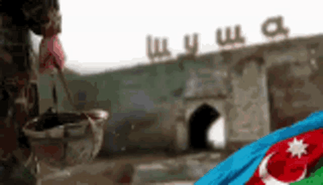 a soldier is holding a bucket in front of a building that has the word shusha written on it