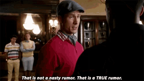 a man in a red sweater is talking to another man in a room .