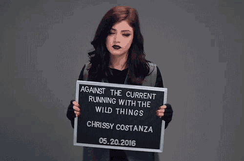 a woman holds a sign that says against the current running with the wild things