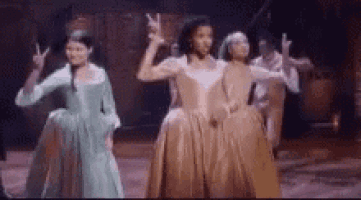 three women in dresses are dancing on a stage .