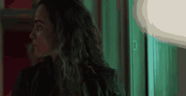a woman with long curly hair is standing in front of a green door