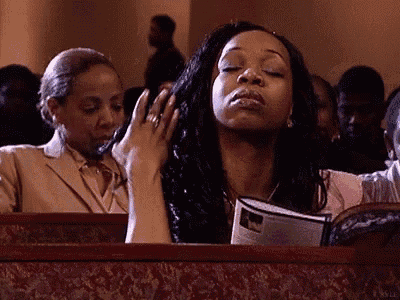 a woman is sitting in a church with her eyes closed and her hands on her head .