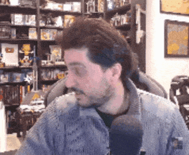 a man with a beard is sitting in front of a microphone