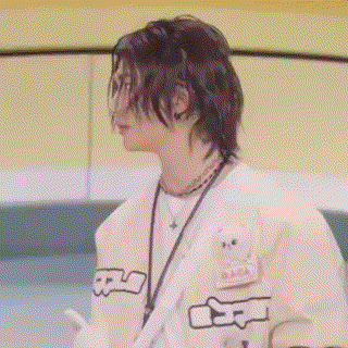 a young man with long hair is wearing a white shirt and a lanyard .