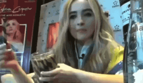 a woman is holding two glasses in front of a sign that says ' california carpenter ' on it