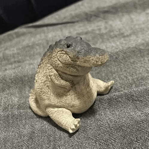 a statue of a crocodile is sitting on a grey cloth