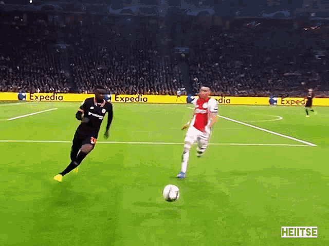 two soccer players on a field with expedia banners