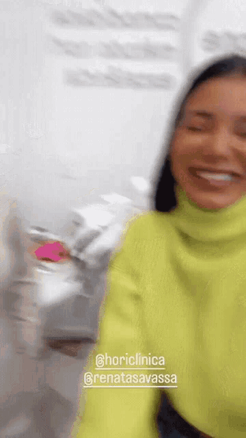a woman in a neon yellow sweater is smiling in a blurry photo taken by @horiclinica and @renatasavassa