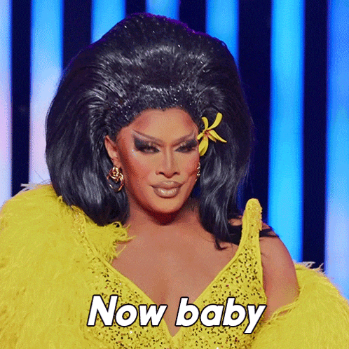 a drag queen is wearing a yellow outfit and says now baby