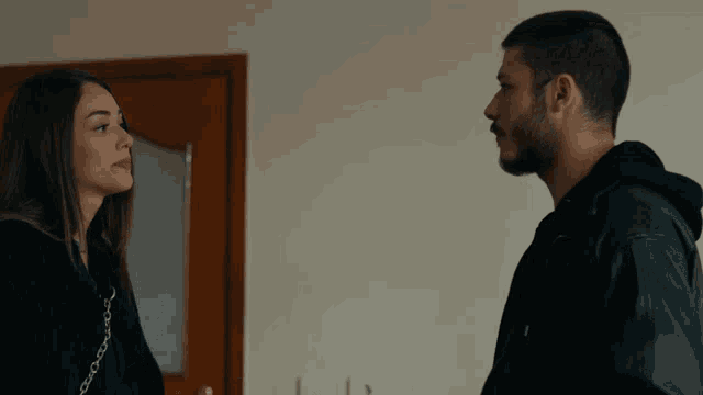a man and a woman standing next to each other looking at each other